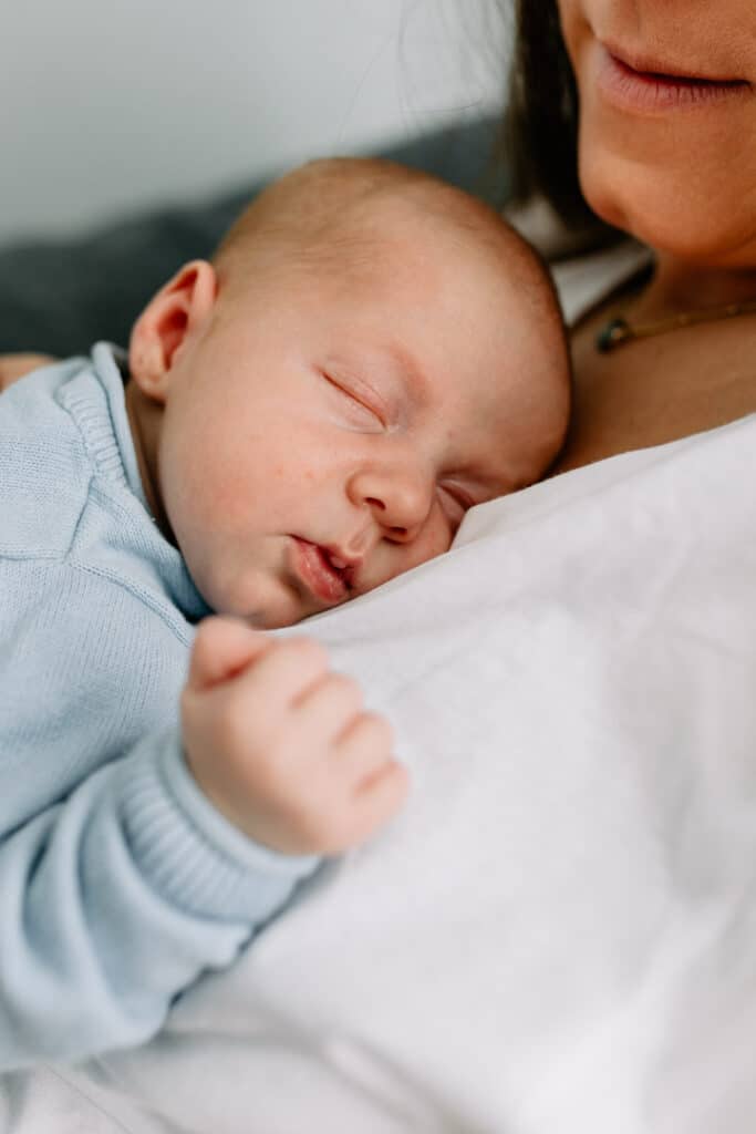 Mum is cuddling her newborn baby boy. boy is sleeping on mummy's chest. Newborn photo shoot in Hampshire. Ewa Jones Photography