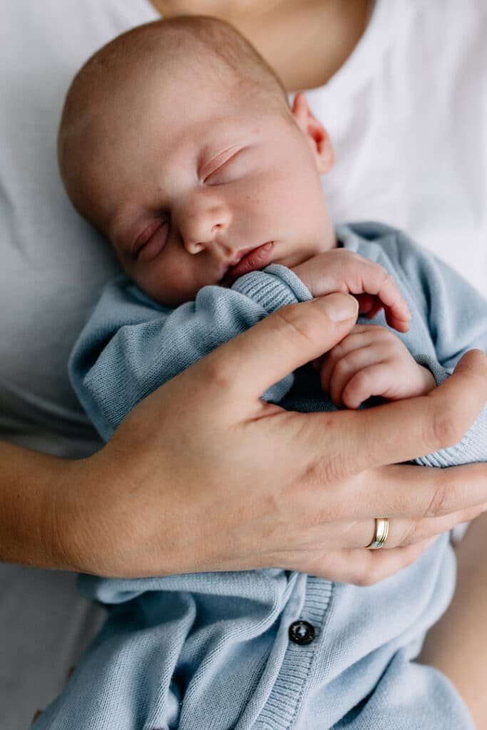 close up image of newborn baby boy that is being held by his mum. Newborn baby is sleeping. Newborn photo shoot in Basingstoke, Hampshire. Ewa Jones Photography