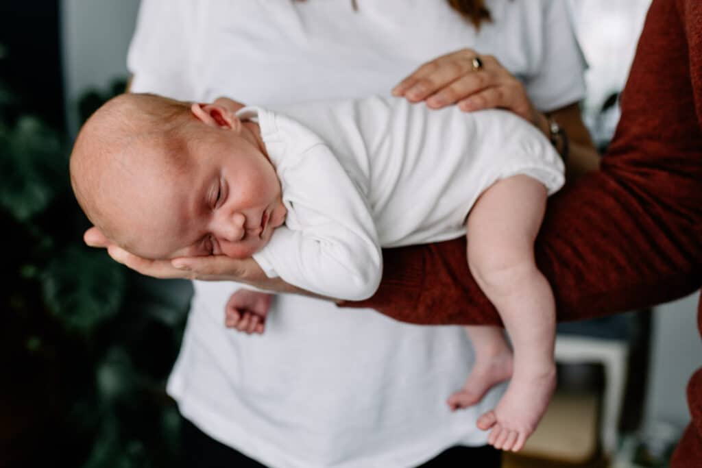 Newborn baby boy is sleeping and dad is holding him on his arm. Newborn photographer in Hampshire. Ewa Jones Photography