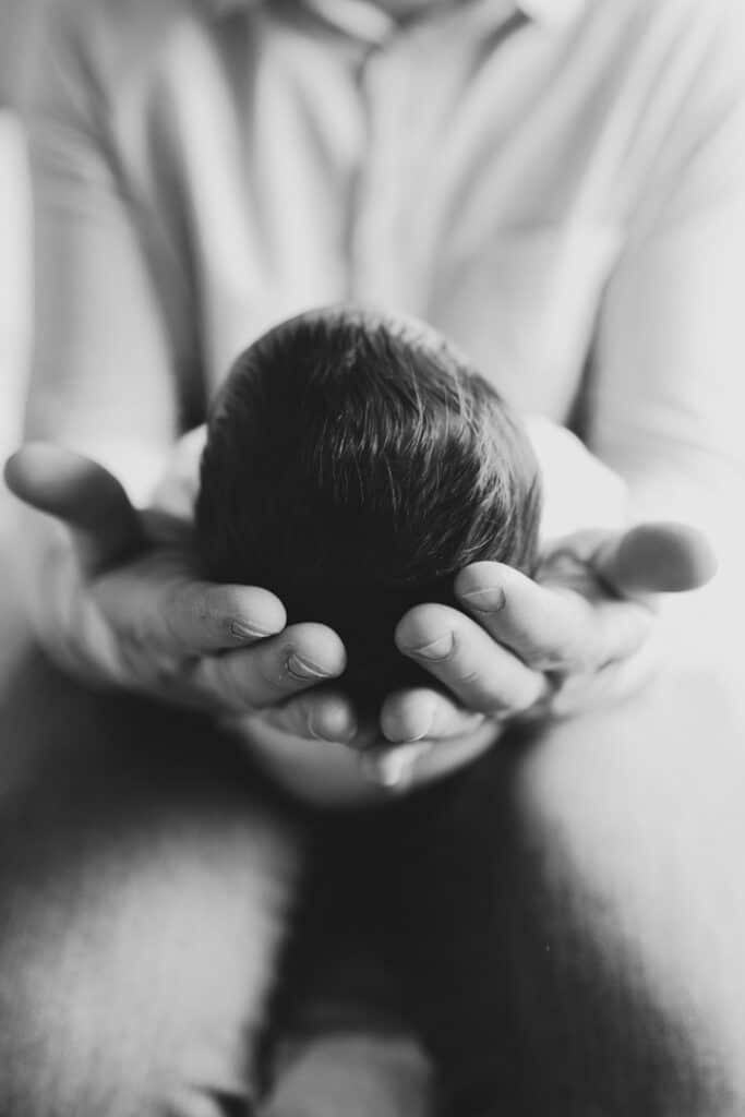 Dad is holding his newborn baby girl. Close up on the newborn baby head. Newborn photographer in Basingstoke, Hampshire. Ewa Jones Photography