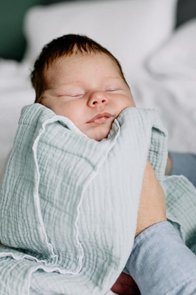 newborn baby girl is sleeping and her dad is supporting her head. lifestyle newborn photo session in Hampshire. Ewa Jones Photography