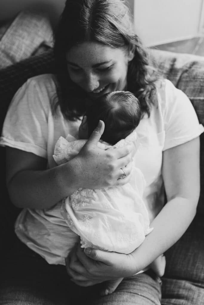 mum is holding her newborn baby and giving her cuddles. Black and white image of beautiful mum and baby connection. Newborn photographer in Basingstoke, Hampshire