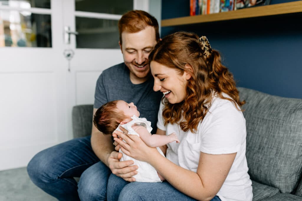 mum and dad are looking down at their baby girl. Beautiful newborn photo shoot at home.lovely natural image of family. Newborn lifestyle photo shoot in Hampshire. Ewa Jones Photography