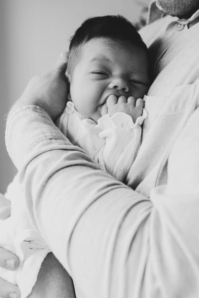 black and white image on dad holding a newborn baby girl. Natural lifestyle newborn photo session in Hampshire. Ewa Jones Photography