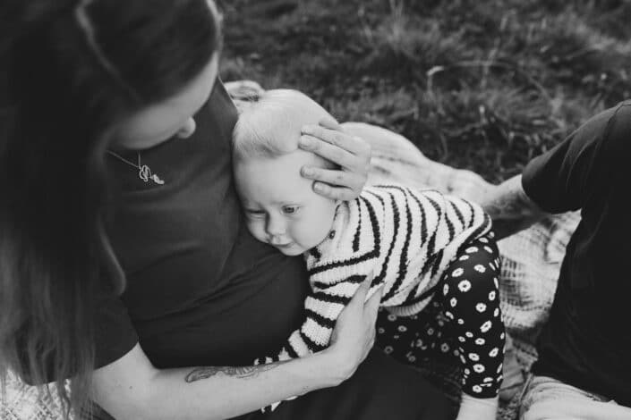 Expecting mum is holding close her older daughter who is listening to the baby. Maternity photography in Basingstoke, Hampshire. Ewa Jones Photography