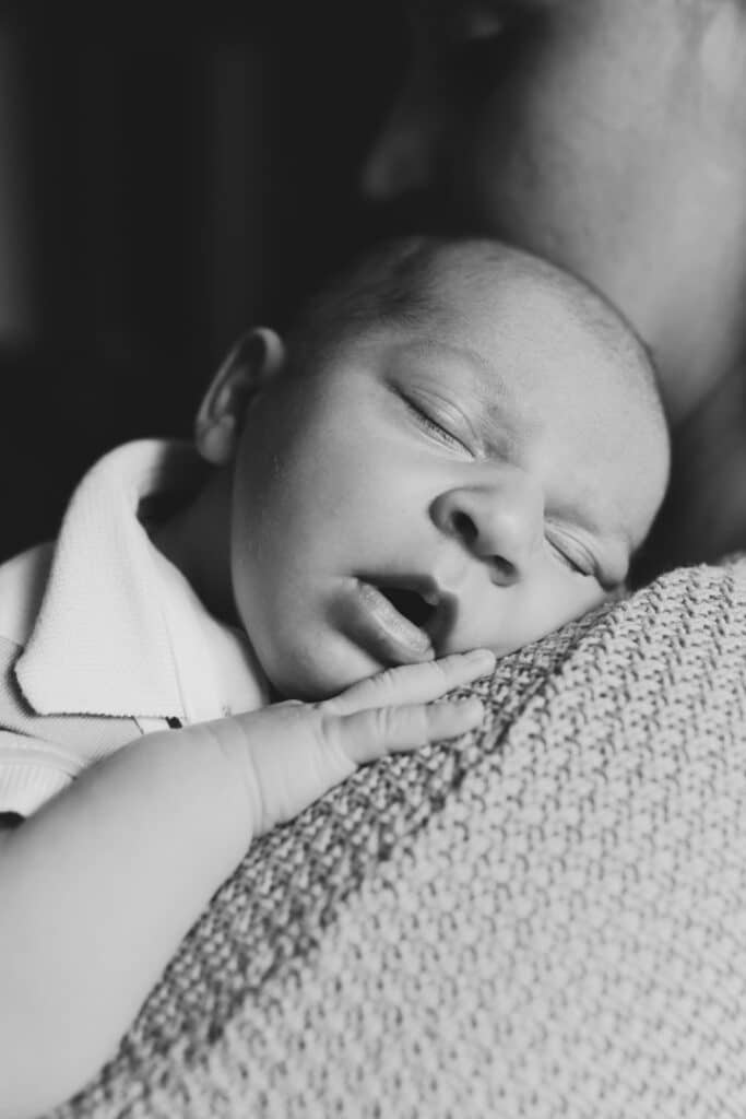 Mum is holding her newborn baby boy on her shoulder and newborn boy is sleeping. Newborn photography in Hampshire. Ewa Jones Photography