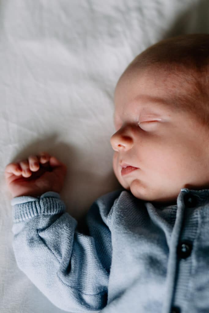 Newborn baby boy is laying on bed and sleeping. Newborn photographer in Basingstoke. Ewa Jones Photography