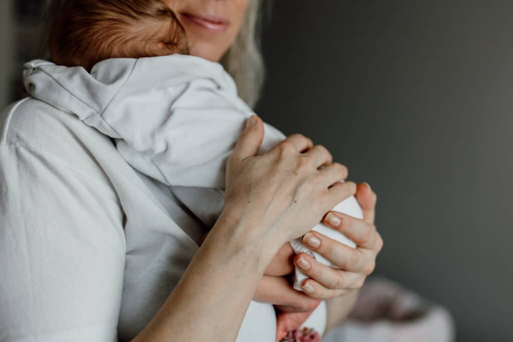 Mum is holding her newborn baby girl high up and supporting her bottom. newborn photographer in Hampshire. Ewa Jones Photography