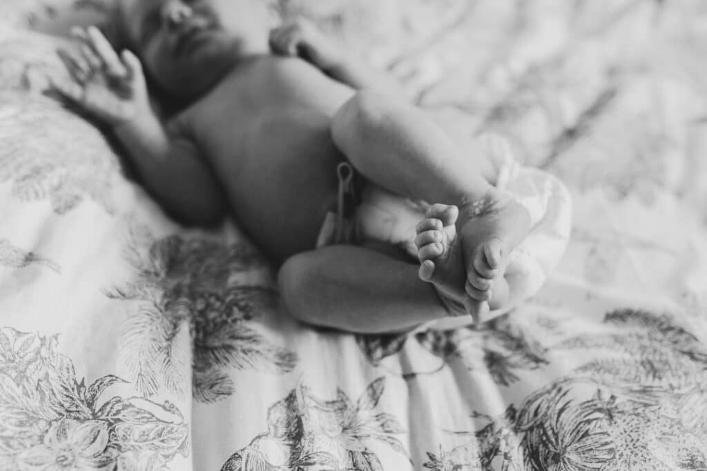 black and white image of newborn baby feet. newborn baby boy is laying on bed sleeping. Newborn photographer in London. Ewa Jones Photography