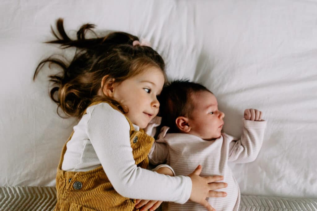 little girl is laying with new newborn sister. My favourite newborn photographs of 2021. Basingstoke photographer. Ewa Jones Photography