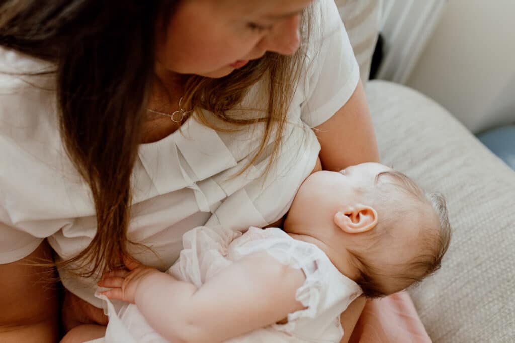 Mum is breastfeeding her little baby girl. Candid lifestyle photography of mum and baby daughter. Newborn photoshoot in Hampshire. Ewa Jones Photography