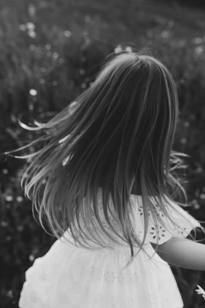 little girl is dancing and her hair is moving as she is turning around. Natural photograph. Family photo shoot in Basingstoke, Hampshire. Ewa Jones Photography