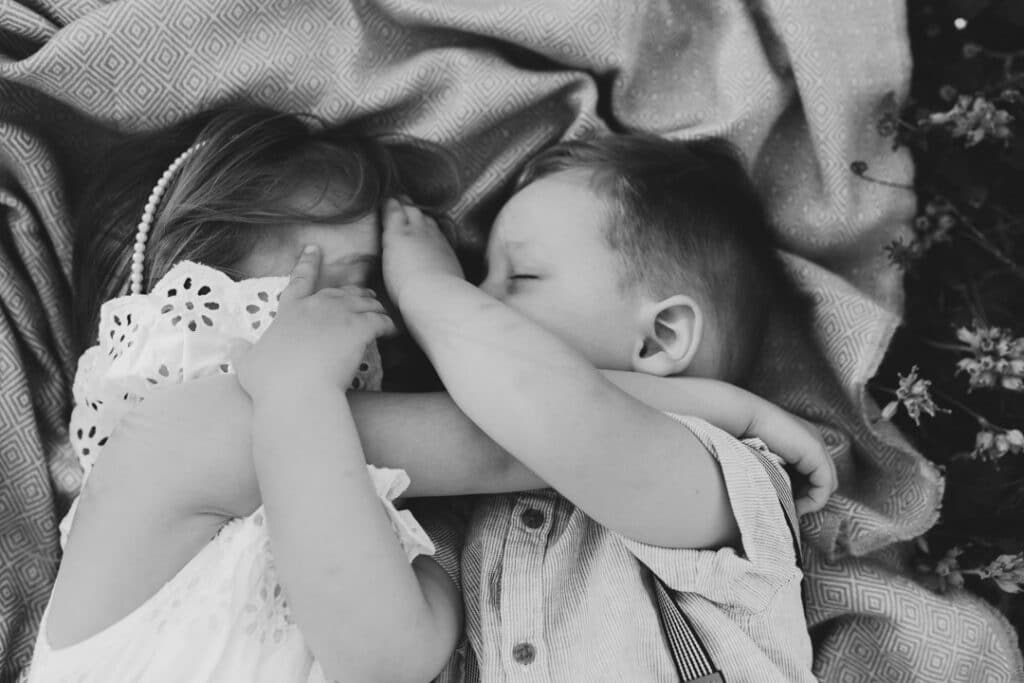 brother and sister are laying on the blanket and cuddling to each other. candid photograph of siblings. family photographer in Hampshire. Ewa Jones Photography