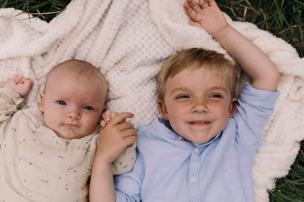Two brothers are laying on the blanket and smiling. they are holding hands together. Family photo shoot in Hampshire. Ewa Jones Photography
