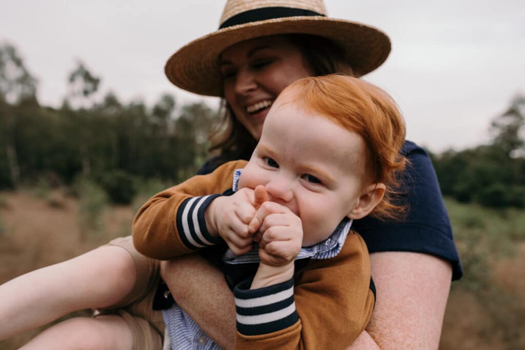 Mum is holding her little boy in her arms. He is looking at the camera and smiling. family photographer in Basingstoke, Hampshire. Ewa Jones Photography