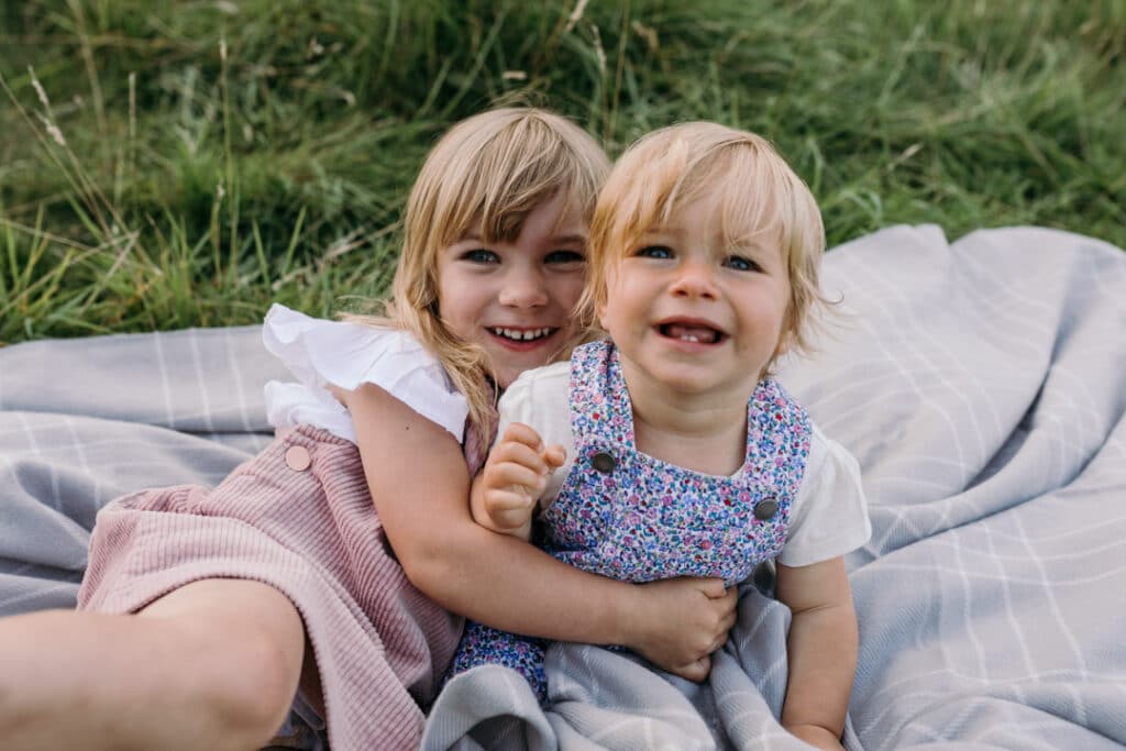 two sisters are cuddling to each other during summer family photo session. Basingstoke photographer. Ewa Jones Photography