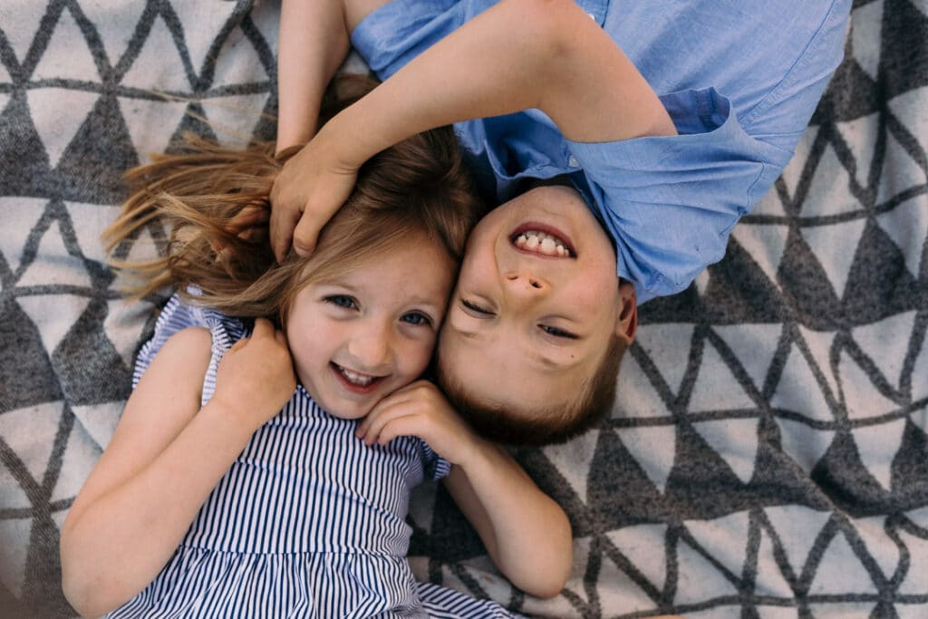 brother and sister are laying on the blanket and looking up. They are wearing blue coloured outfits. family photographer in Hampshire. Ewa Jones Photography