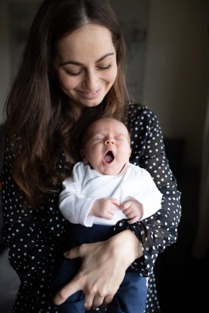 Mum is holding her newborn baby and the newborn baby is yawning. Newborn photo shoot in Hampshire. Ewa Jones Photography