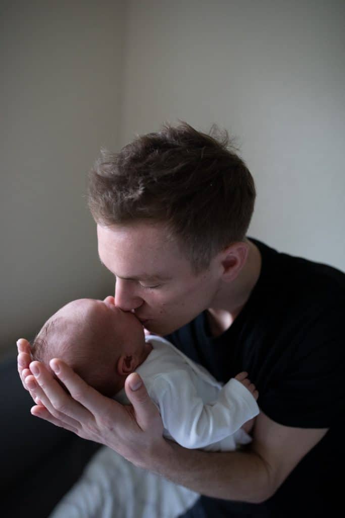 Black and white photograph of dad kissing his newborn baby son. Newborn photo shoot in Hampshire. Hampshire newborn photographer. Ewa Jones Photography