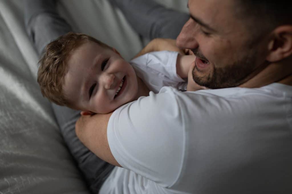 Dad is cuddling his little boy who is smiling to the camera. family photographer in Basingstoke, Hampshire. Ewa Jones Photography