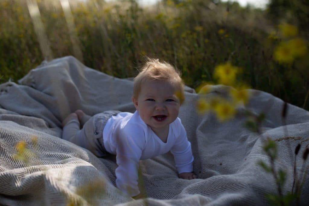 little baby boy is looking at the camera and smiling. Family photographer in Basingstoke, Hampshire. Ewa Jones Photography