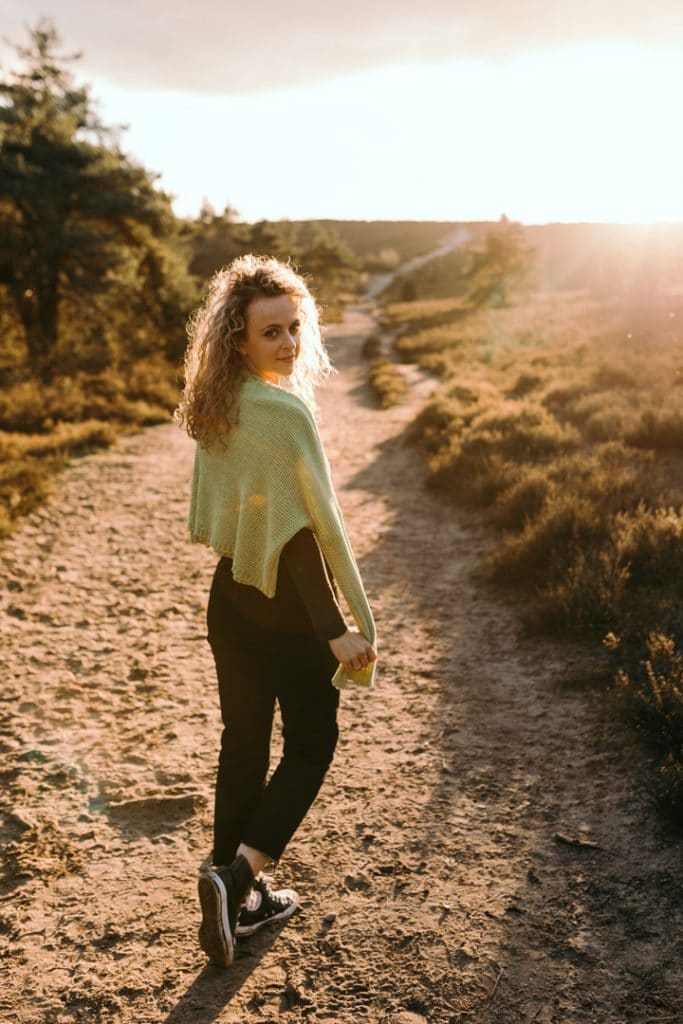 Female is walking down the path and looking at the camera. she is wearing black jeans and green cardigan. natural female photo shoot in Hampshire. Basingstoke photographer. Ewa Jones Photography