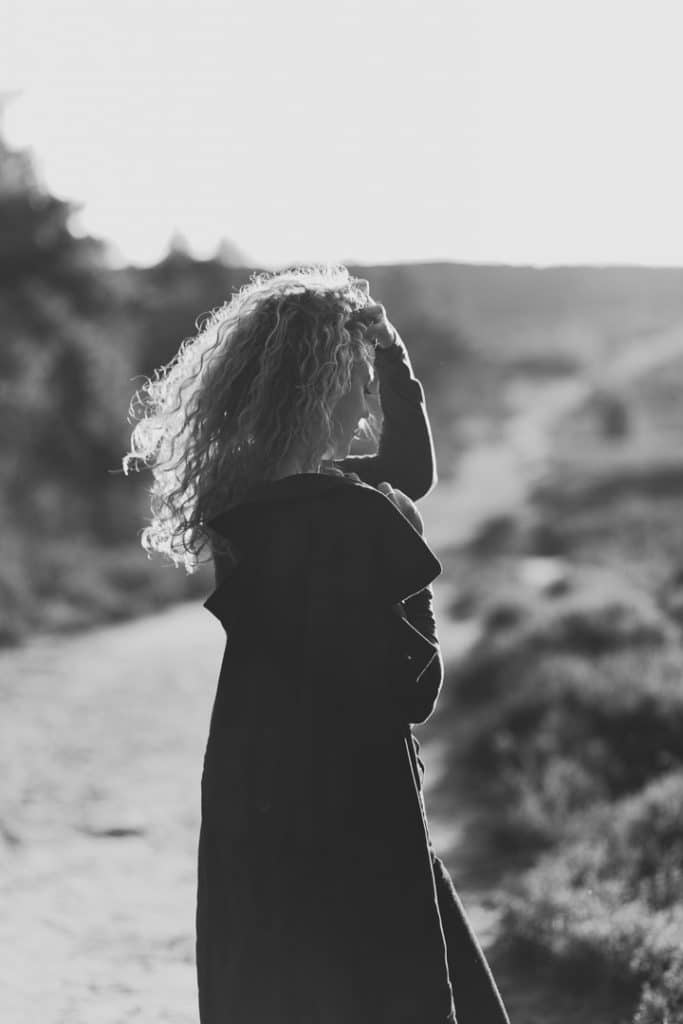 Black and white image of a female. she is holding her coat and looking down. Female photo shoot in Hampshire. Basingstoke photographer. Ewa Jones Photography