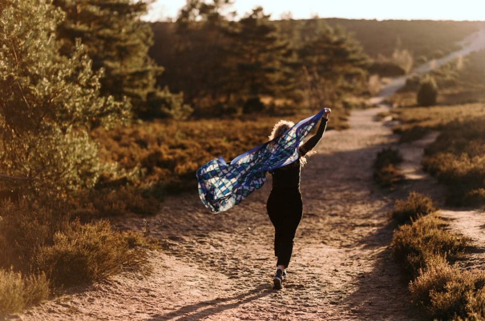 Woman is running on the path and had her scarf floating in the air. Female photo session in Hampshire. Ewa Jones Photography