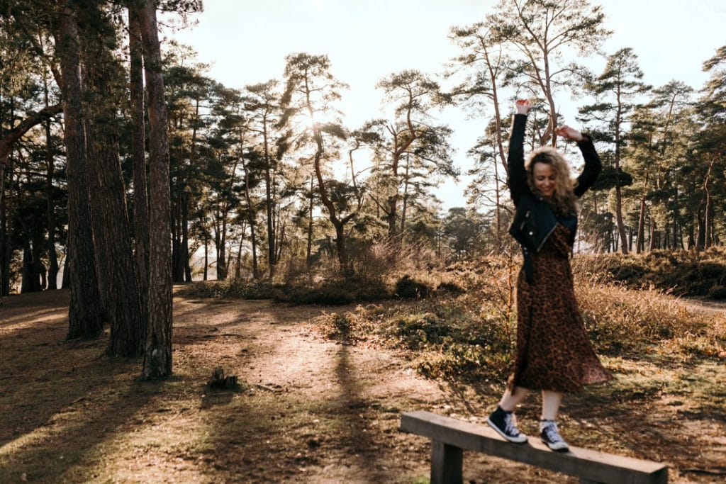 Female is dancing on the bench and smiling. lovely outdoor female photo session in Hampshire. Female photo session with Fi. Ewa Jones Photography