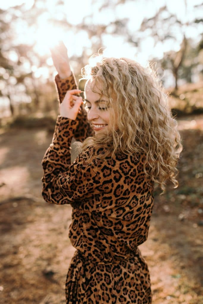 Female is smiling and has her hands up in the air. sun is shining behind her. female photo session with Fi. Basingstoke photographer. Ewa Jones Photography