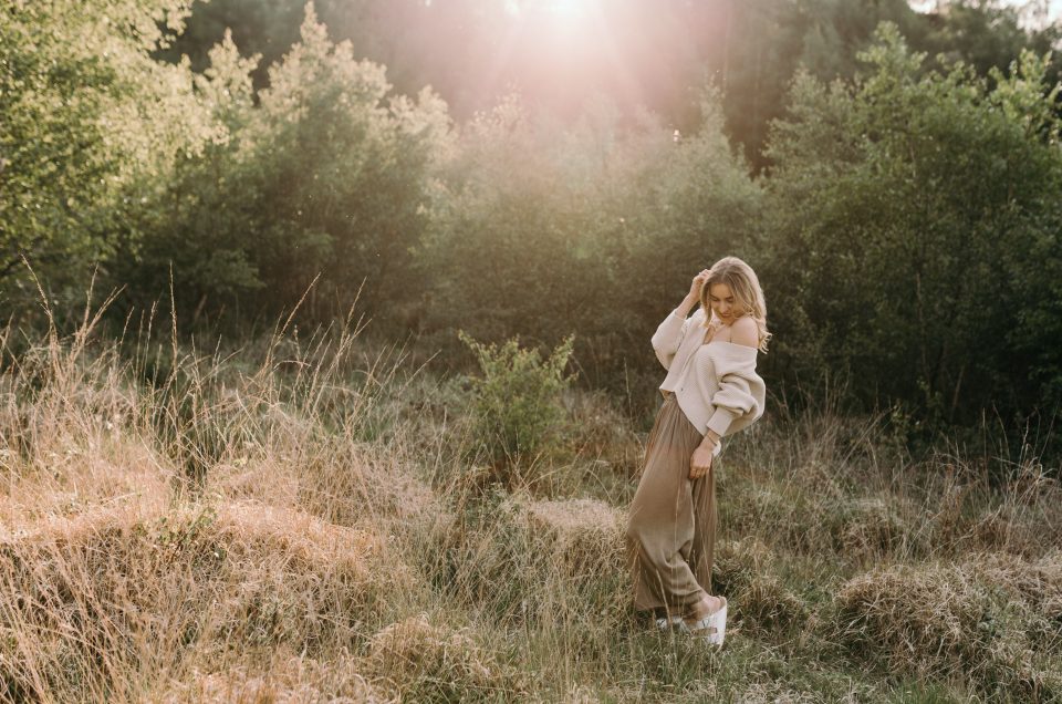 Mother's day photo session. Young woman is standing in the field and looking down. sunset photoshoot. Basingstoke photographer. Ewa Jones Photography