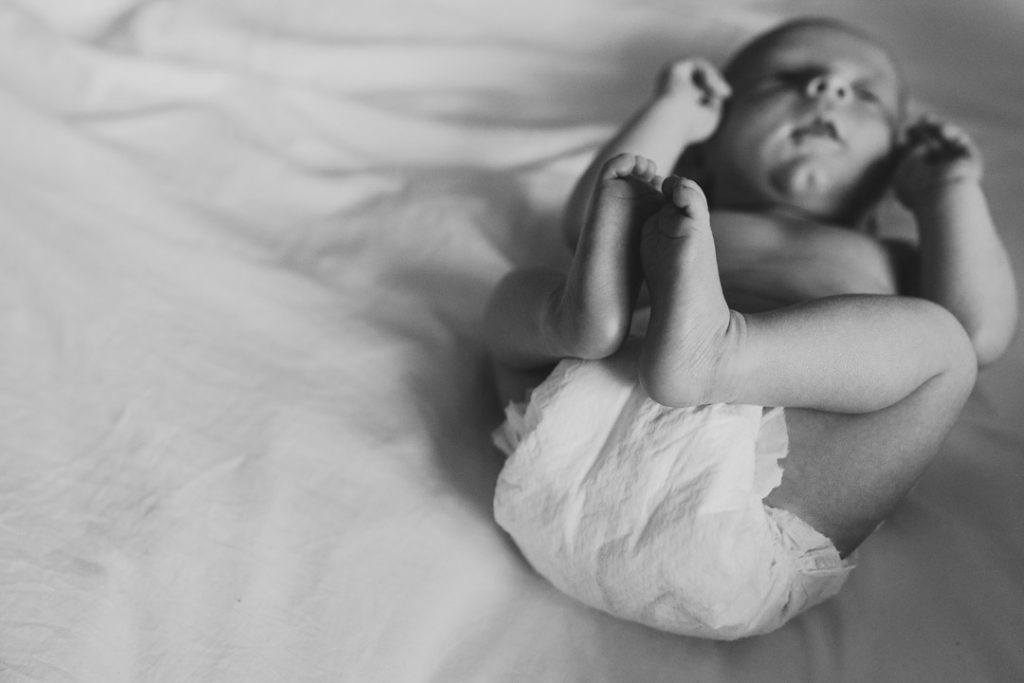 Black and white photograph of newborn baby feet. Newborn baby is laying on bed. Newborn photography in Basingstoke, Hampshire. Ewa Jones Photography