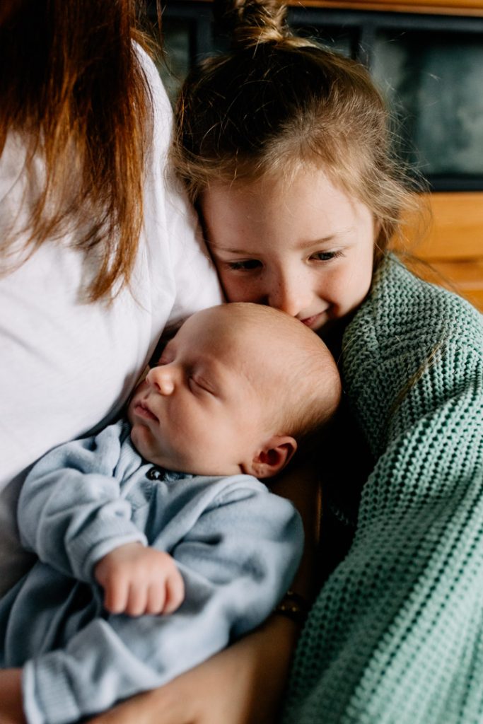 Older sister is cuddling up to her newborn baby brother. Newborn photo shoot in Basingstoke, Hampshire. Ewa jones Photography