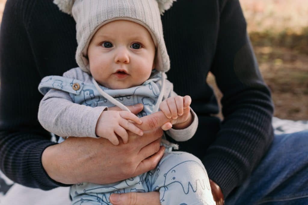 Little boy is holding daddy's finger and looking at the camera. Hampshire photographer. Ewa Jones Photography