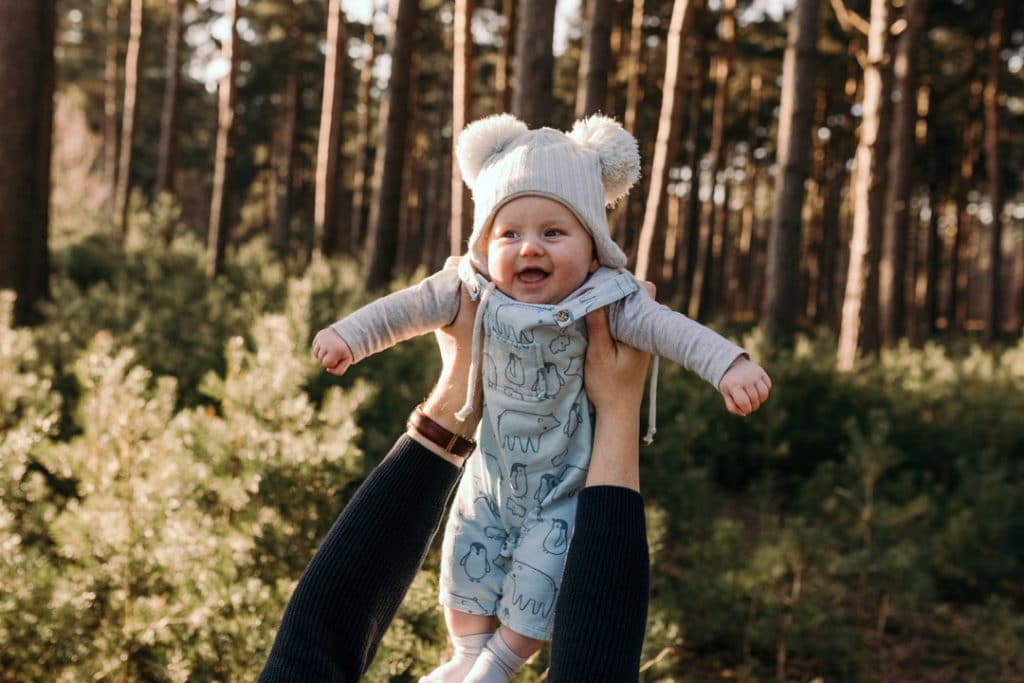 Dad is lifting his baby boy up in the air and the boy is laughing. Family photo shoot in Hampshire. Ewa Jones Photography