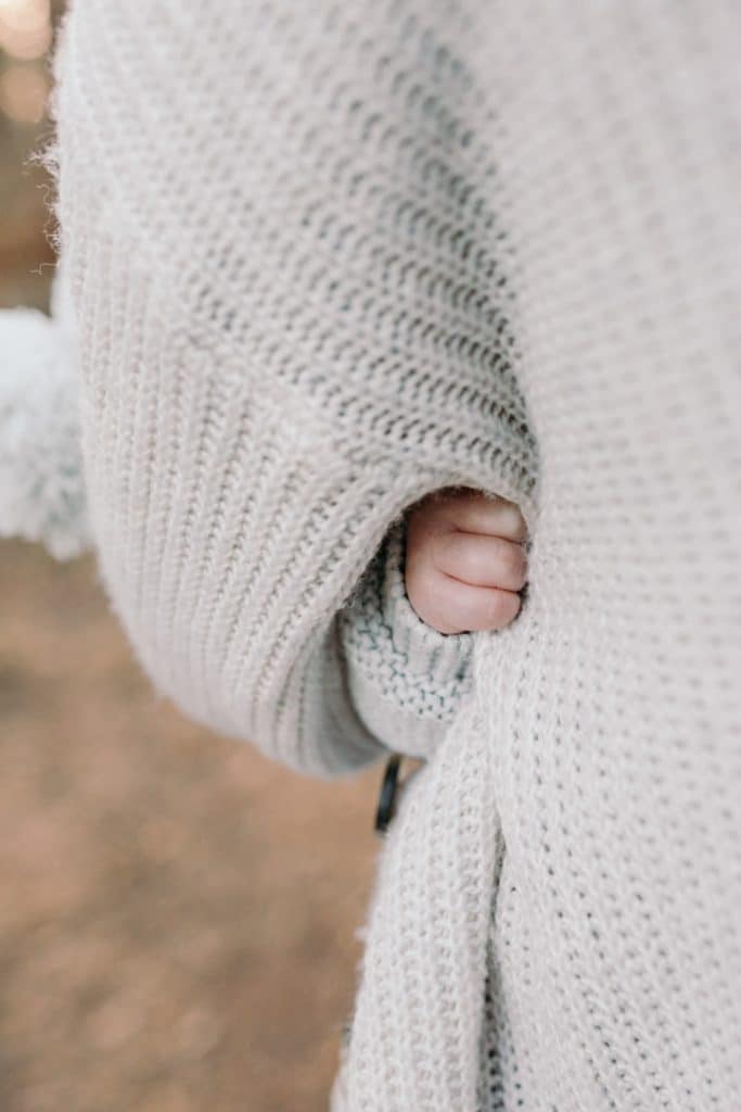 Close up detail of a newborn baby hand holding on to mummy's jumper. Natural lifestyle family photographer in Basingstoke, Hampshire. Ewa Jones Photography