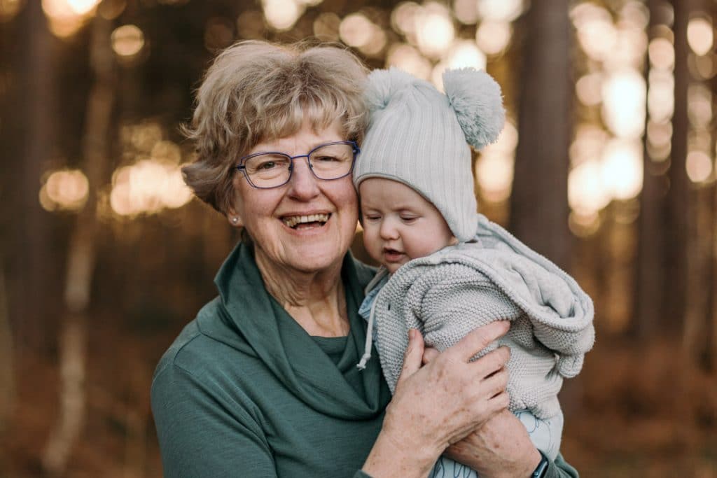 Grandma is holding baby boy in her arms and smiling. natural family photo session in Hampshire. Ewa Jones Photography