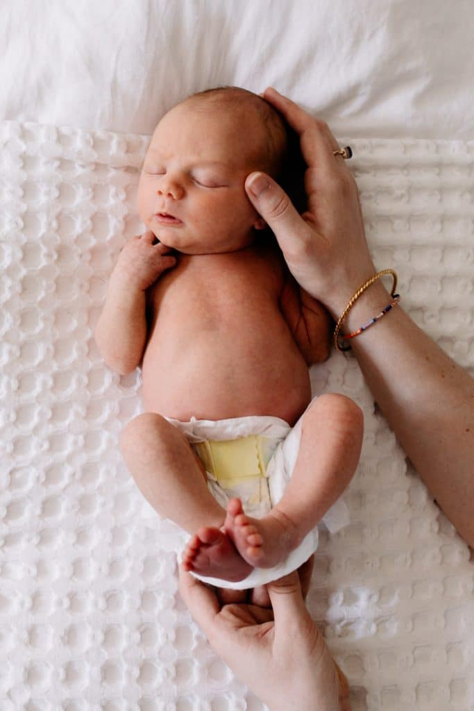 Newborn baby boy is laying on the bed and sleeping. Newborn photographer in Hampshire. Ewa Jones Photography