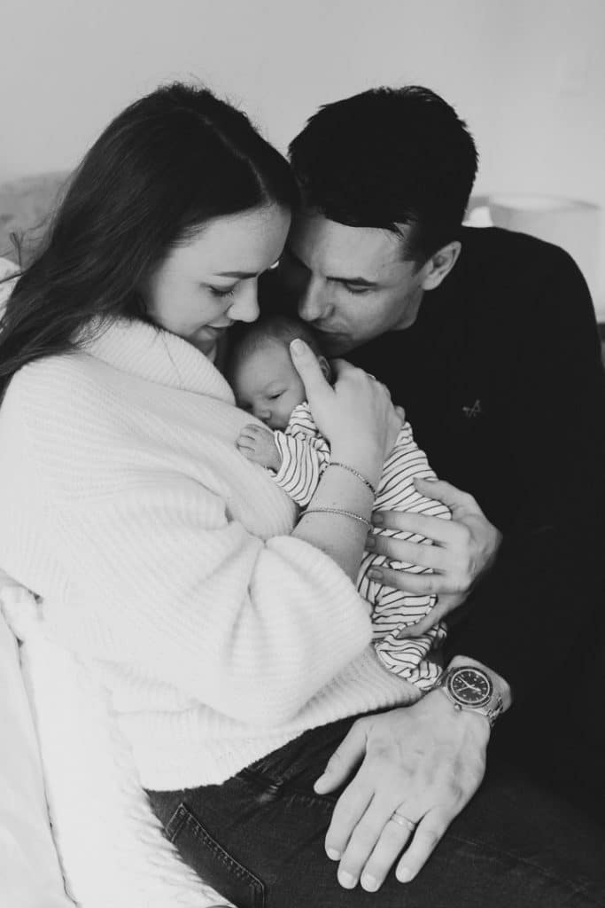 mum and dad are cuddling their newborn baby. lovely candid lifestyle newborn photoshoot. Newborn photographer in Hampshire. Ewa Jones Photography