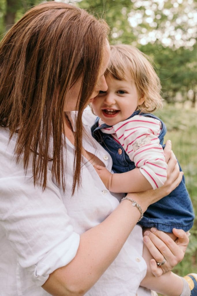mum is holding her girl and looking at her. little girl is smiling. Family photo session in Hampshire. Ewa Jones Photography