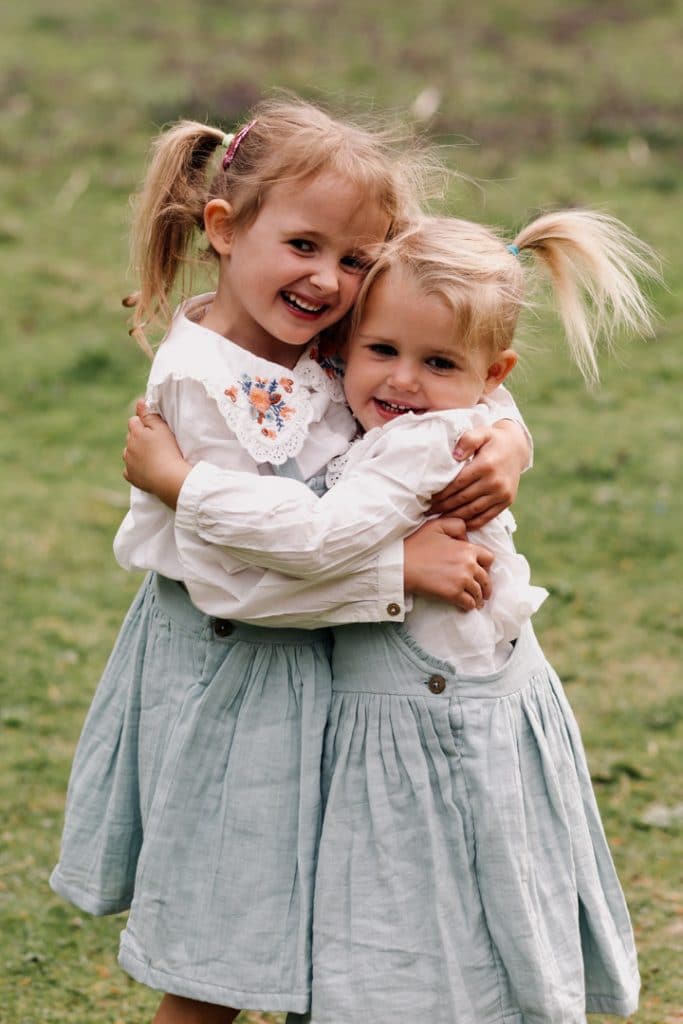 Two sisters are cuddling. What to wear for a family photoshoot. Family photographer in Basingstoke, Hampshire. Ewa Jones Photography
