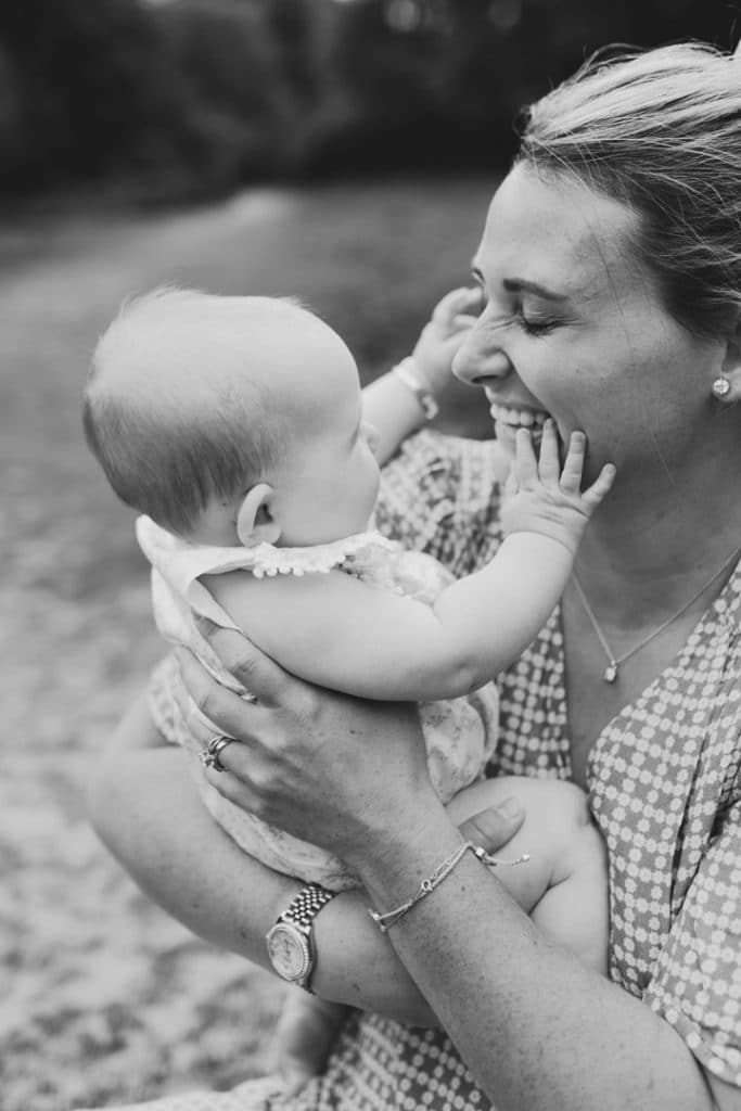 Mum is holding her baby girl and baby girl is touching mums face. Natural lifestyle family photoshoot in Hampshire. Basingstoke family photographer. Ewa Jones Photography