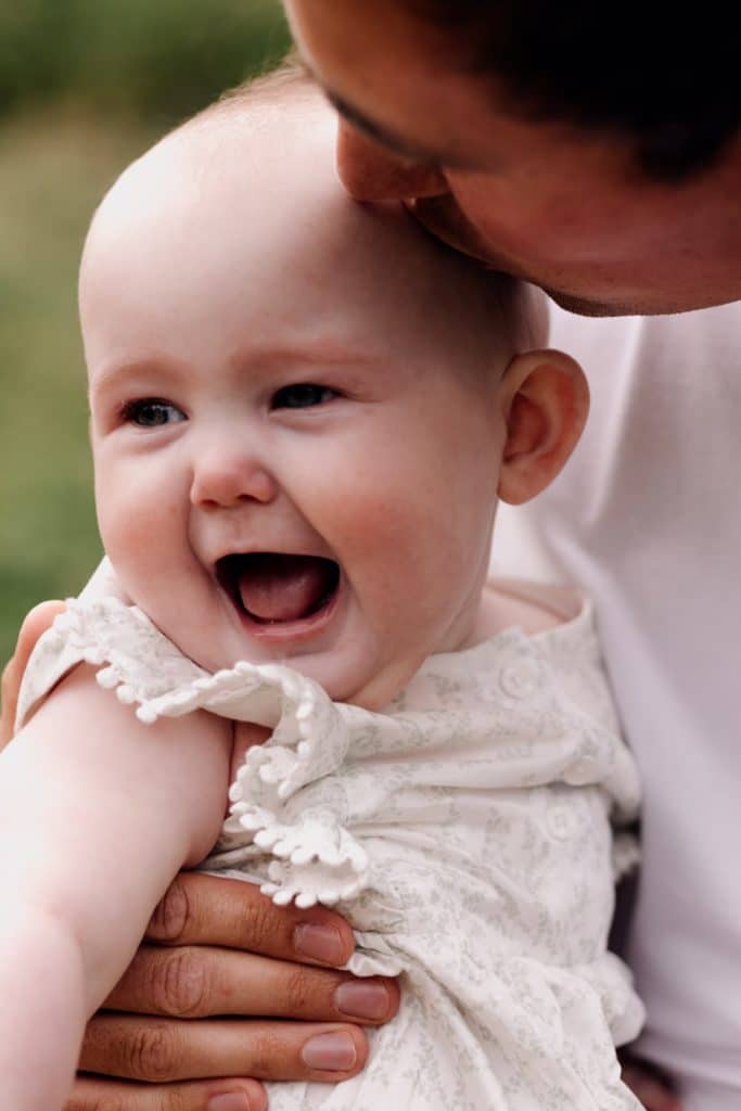 Dad is holding his baby girl and kissing her. Hampshire photographer.. Basingstoke photographer. Ewa Jones Photography