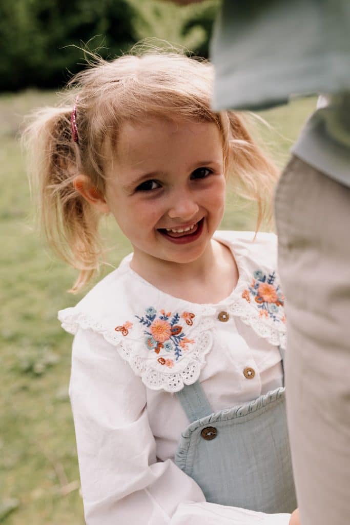 Girl is hiding behind dad and plays peek a boo. Family photoshoot in Basingstoke. Ewa Jones Photography