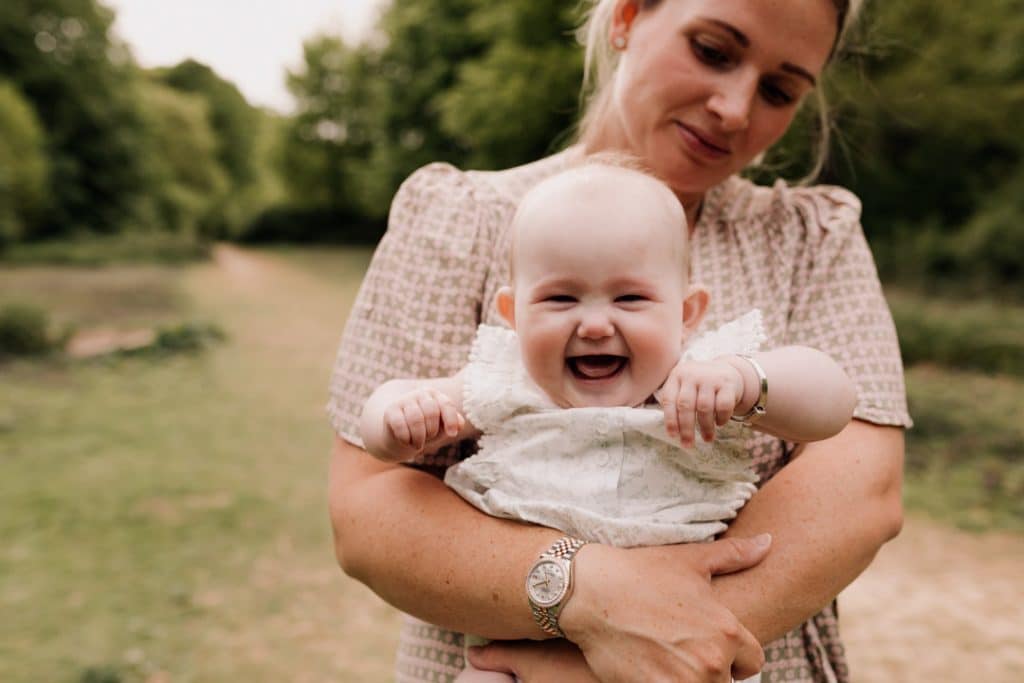 Baby girl is laughing to the camera. Family photo session in Hampshire. Ewa Jones Photography