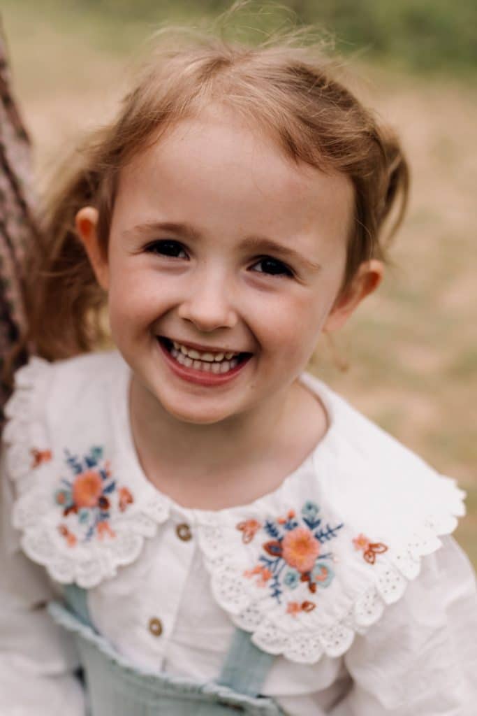 Girl is looking at the camera and smiling. What to wear for a family photo session. Hampshire family photographer. Ewa Jones Photography