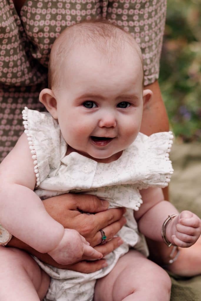 baby girls is looking at the camera and smiling. family photographer in Basingstoke. Ewa Jones Photography