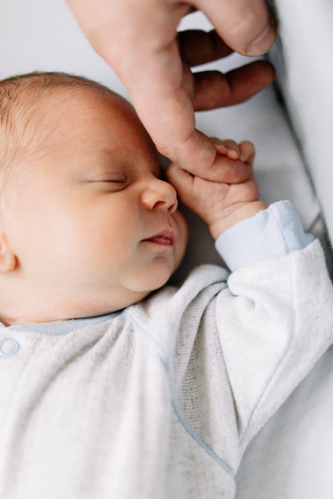 Newborn baby boy is holding his dad finger. Lifestyle newborn photo session in London. Ewa Jones Photography