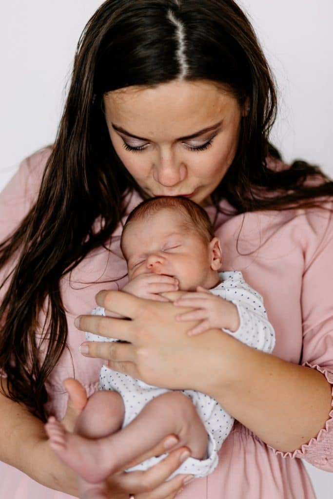 Mum is kissing her newborn baby boy in his head and baby boy is sleeping. Newborn photographer in Hampshire. Ewa Jones Photography
