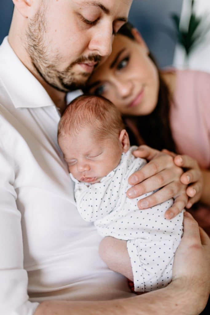 Parents are cuddling up to their newborn baby boy. Newborn photographer in Hampshire. Ewa Jones Photography